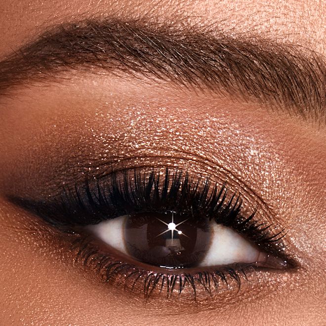 Luxury Palette of Pops in Dazzling Diamonds on brown eye close-up Single-eye close-up of a medium-tone model with brown eyes wearing shimmery gold and brown eyeshadow.