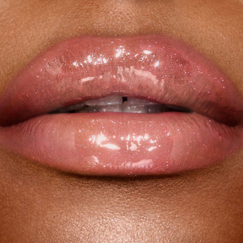 Lips close-up of a deep-tone model wearing a shimmery, gold-coloured lip gloss with rose gold sparkles.