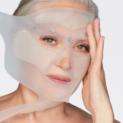 Fair-tone model with mature skin applying a reusable, white-coloured mask, that ensures glowy, flawless, and lifted skin. 
