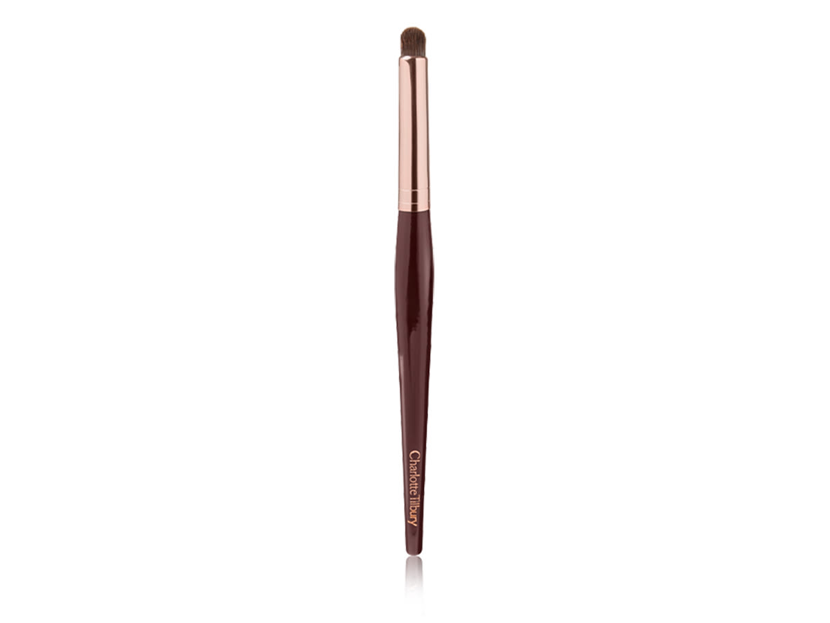 An eyeshadow smudging brush with soft bristles and a rose-gold and dark crimson handle. 