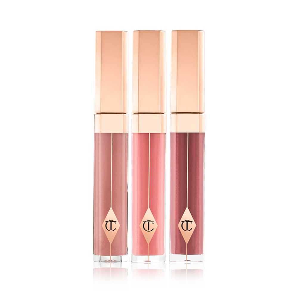 Three high-shine lip glosses in clear tubes with gold-coloured lids in mauve, bubblegum pink, and wine. 