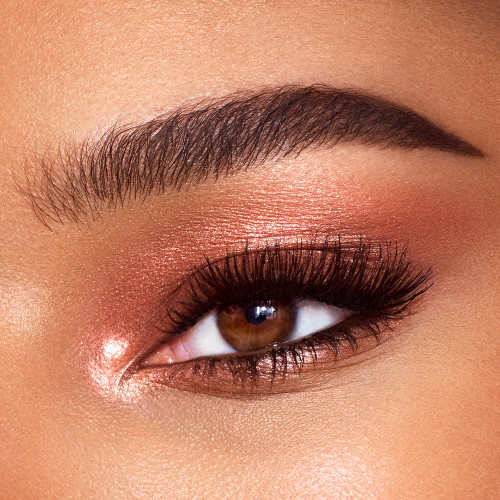 Single-eye close-up of a model with brown eyes with shimmery, coppery-gold-coloured cream eyeshadow. 