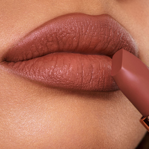 Lips close-up of a medium-tone model wearing a deep, sultry rose-brown nude lipstick with a matte finish.
