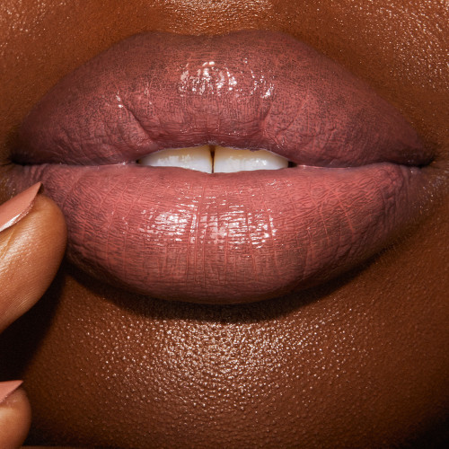 Lips close-up of a deep-tone model wearing a moisturising lipstick lip balm in a nude-pink shade.