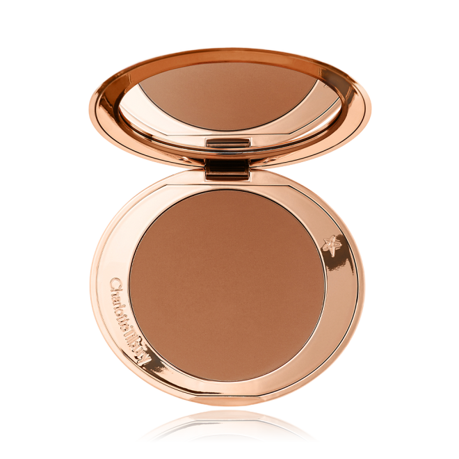 An open mirrored-lid bronzer compact in a tan shade. 