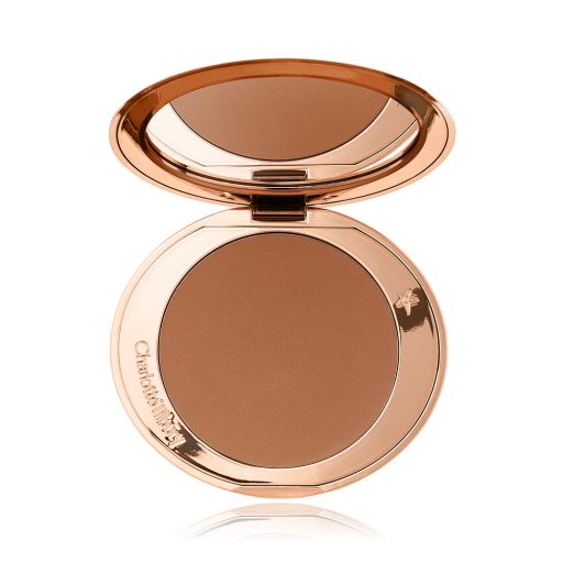 An open mirrored-lid bronzer compact in a tan shade. 