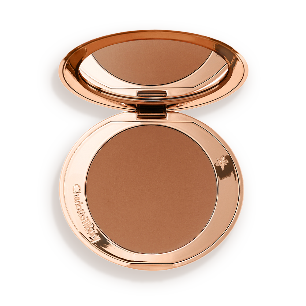 An open mirrored-lid bronzer compact in a tan shade. 