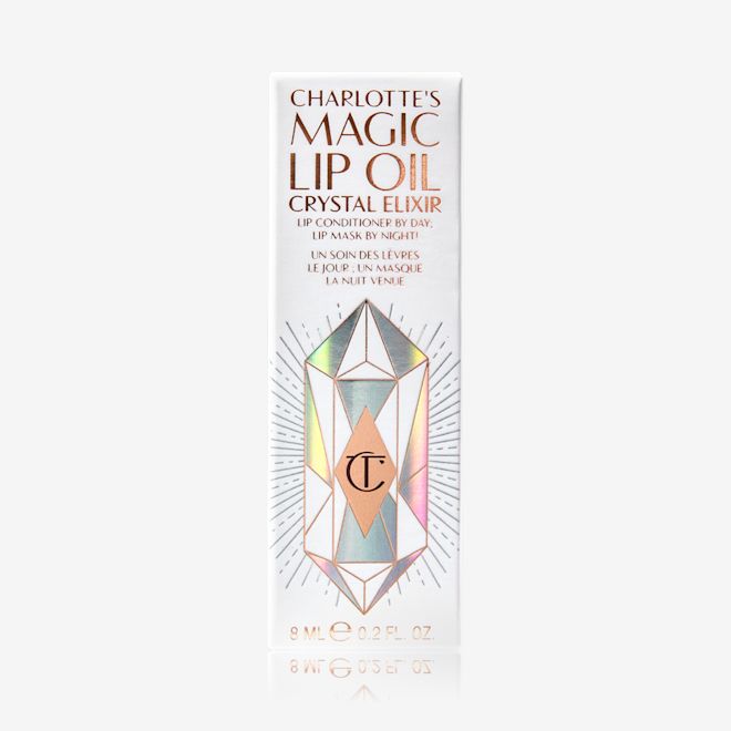 Charlotte's Magic Lip Oil Crystal Elixir packaging A white-coloured lip oil box with shiny, geometric patterns on it, and Magic Lip Oil written on it in rose gold colour.