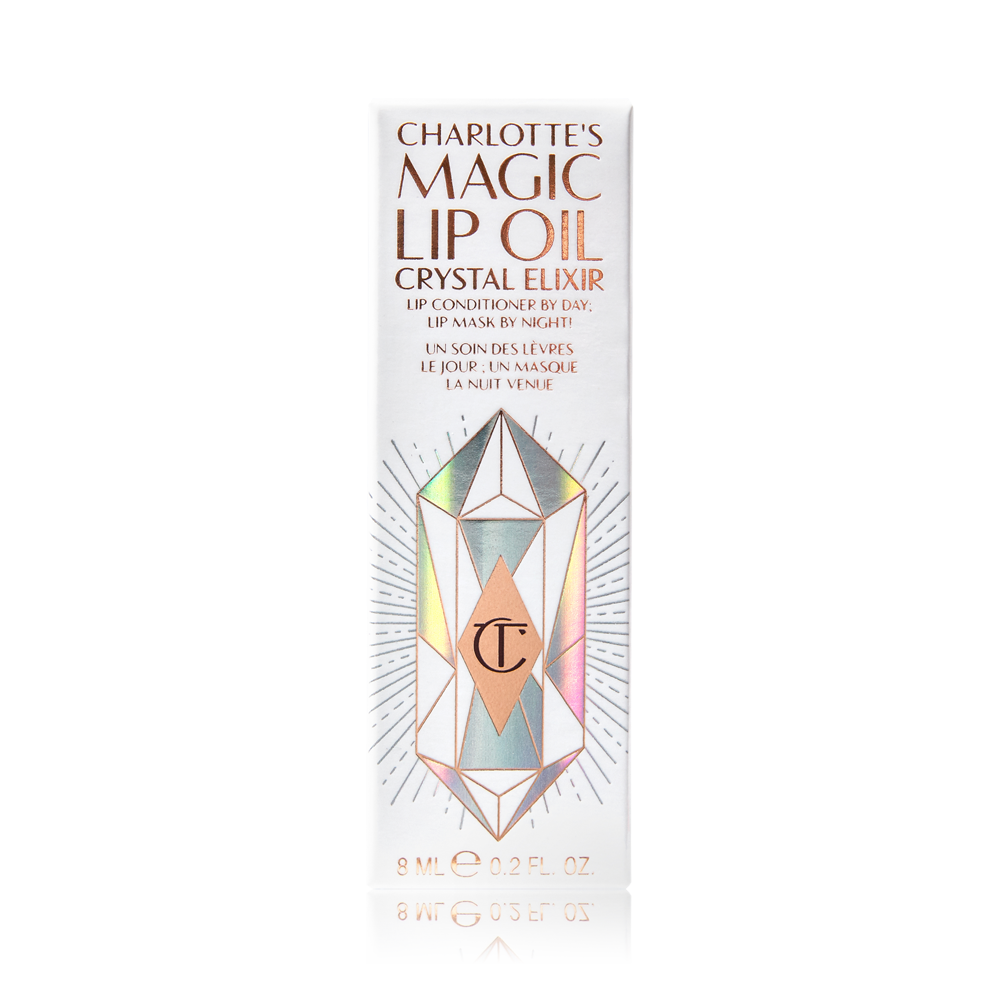 A white-coloured lip oil box with shiny, geometric patterns on it, and Magic Lip Oil written on it in rose gold colour. 