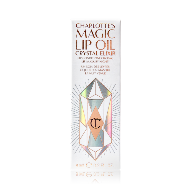 Charlotte's Magic Lip Oil Crystal Elixir Packaging A white-coloured lip oil box with shiny, geometric patterns on it, and Magic Lip Oil written on it in rose gold colour.