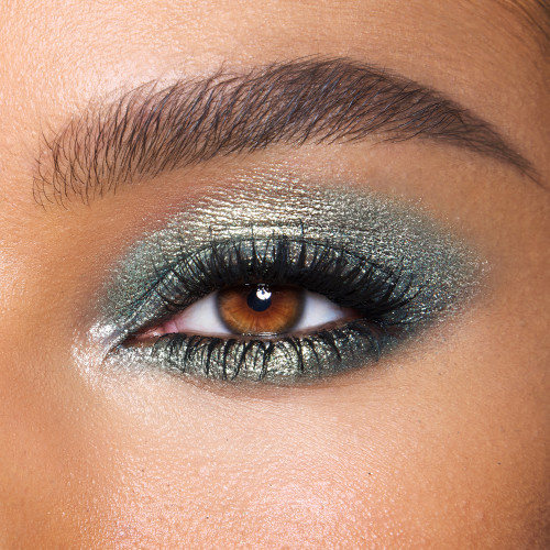 Close-up of a model with brown eyes wearing iridescent emerald green eyeshadow with very fine shimmer. 