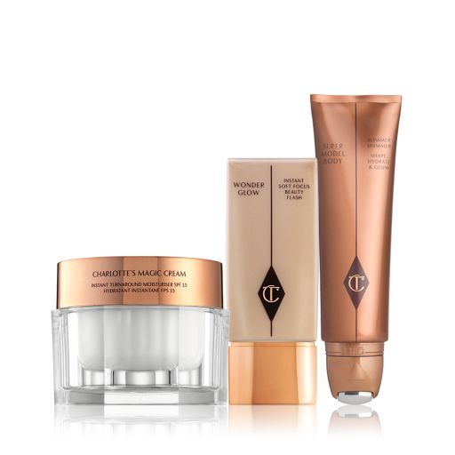 Face cream in a glass jar with a gold-coloured lid, foundation in a rectangular, transparent bottle with a square lid, and a body highlighter wand in a bronze-coloured tube.