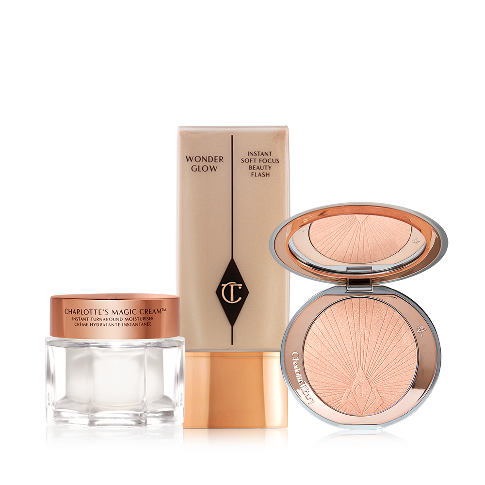 Pearly-white face cream in a glass jar with a gold-coloured lid, foundation in a clear bottle with a gold-coloured lid, and powder highlighter in a soft rose-gold shade in a gold-coloured compact with a mirrored-lid.