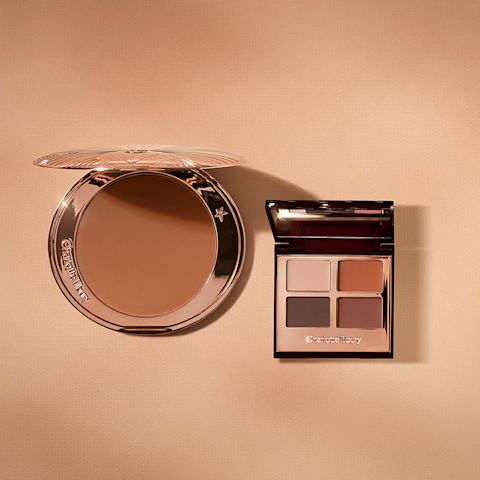 An open bronzer in medium-brown shade in golden-coloured compacts with an open, mirrored lid eye shadow palette with four matte and shimmery eye shadows in shades of brown and champagne.