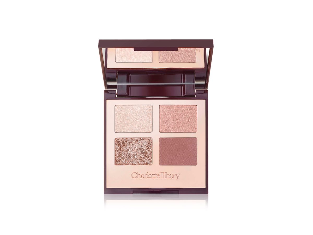 An open, mirrored-lid eyeshadow palette in nude pink, gold, and brown shades. 