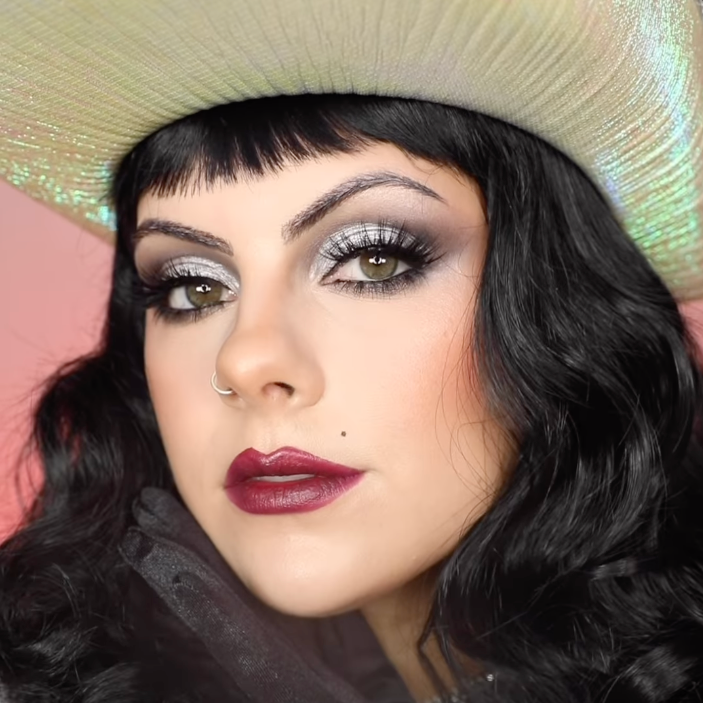 Content creator Sophie Hannah wearing a space cowboy halloween doll makeup look with silver eyeshadow look with dark red lip.
