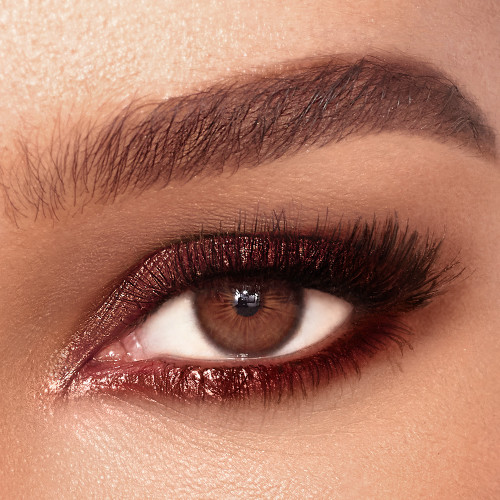 Single-eye close-up of a brown-eyed model wearing shimmery reddish-bronze eyeshadow. 