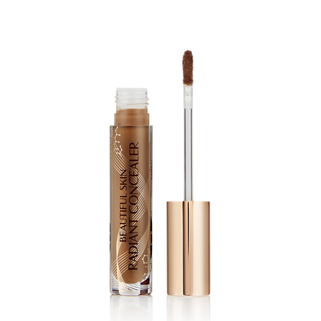 Dark brown radiant concealer in a glass tube with its gold-coloured lid with a doe-foot end next to it, and text on the tube that reads, 'Beautiful Skin Concealer'