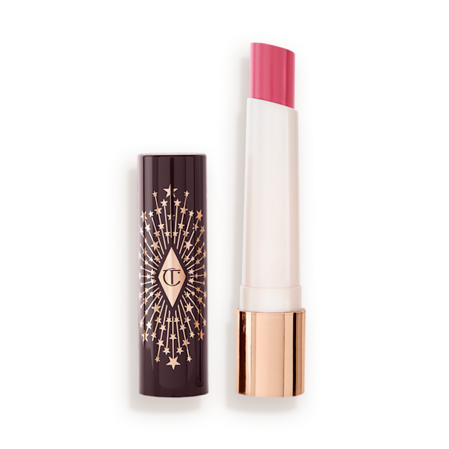 An open lipstick lip balm in a sheer nude pink berry shade, in white and gold tube with a black-coloured lid with gold sparkles all over it.