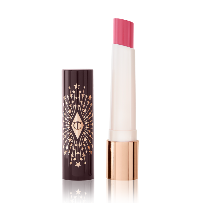 An open lipstick lip balm in a sheer nude pink berry shade, in white and gold tube with a black-coloured lid with gold sparkles all over it.