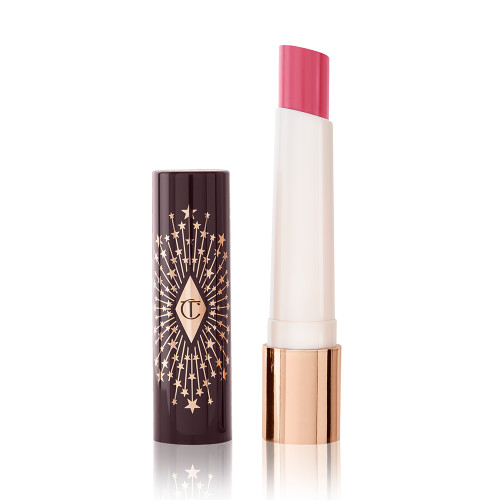 An open lipstick lip balm in a sheer nude pink berry shade, in white and gold tube with a black-coloured lid with gold sparkles all over it.