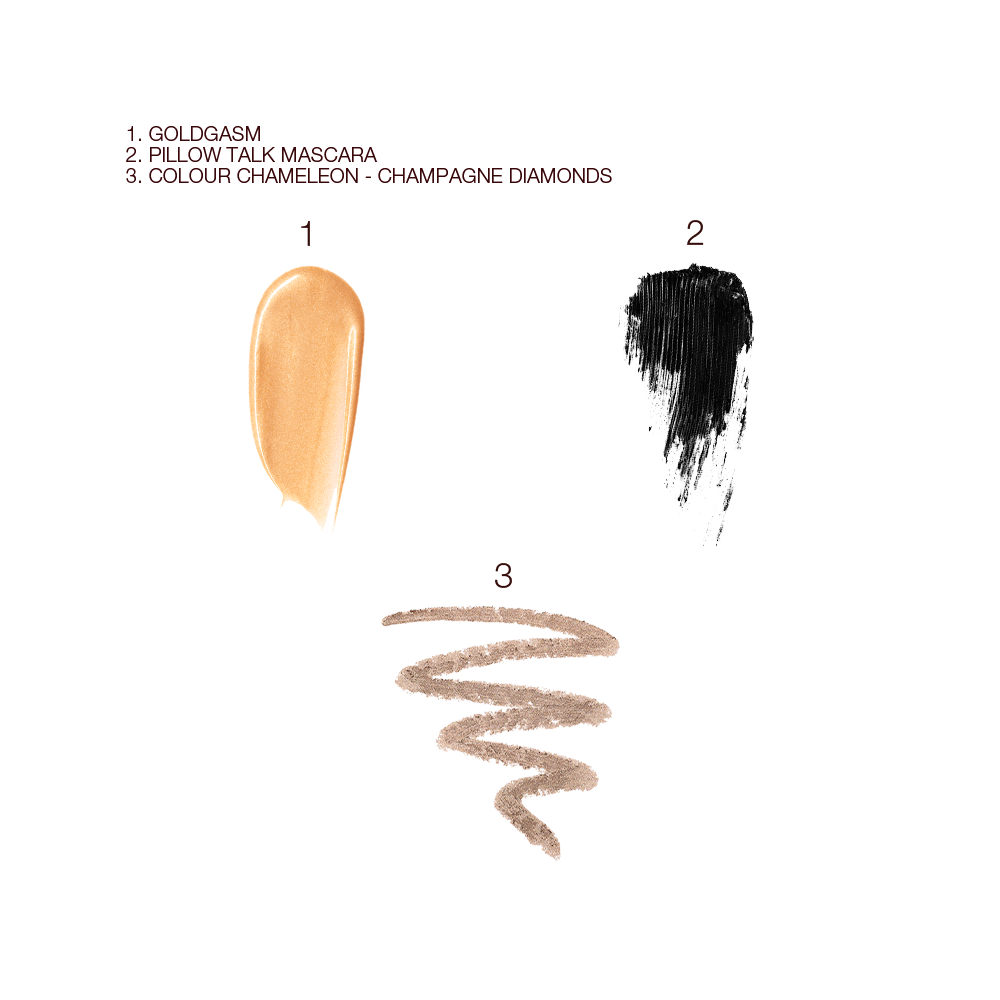 Swatches of liquid highlighter in a soft gold shade, black mascara, and eyeshadow stick in a champagne shade. 