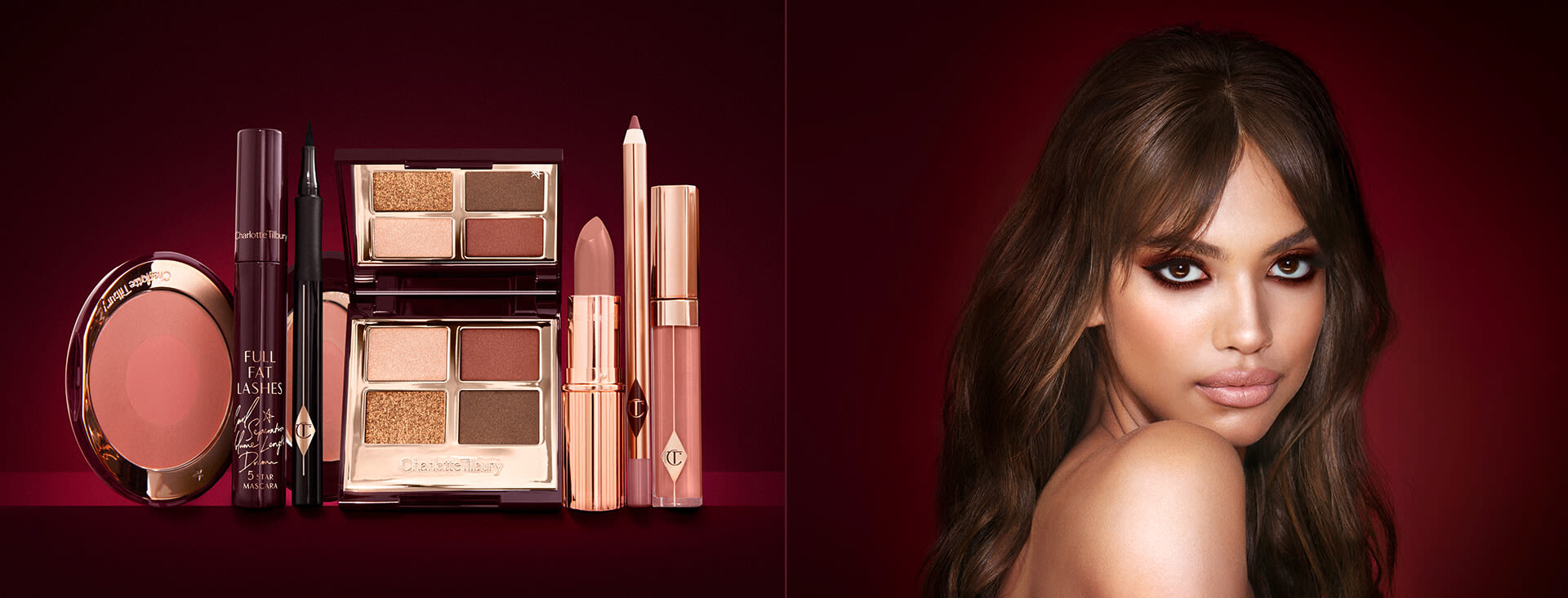 A medium-tone model with brown eyes wearing smokey brown and gold eye makeup with warm pink blush and glossy nude-pink lips next to a makeup kit that includes an open, mirrored-lid eyeshadow palette in matte and shimmery brown and gold shades, an open black eyeliner pen, a mascara in a dark-crimson colour scheme, a berry-rose lipstick with a matching lip liner pencil, nude pink lip gloss, and an open two-tone blush in warm pink. 
