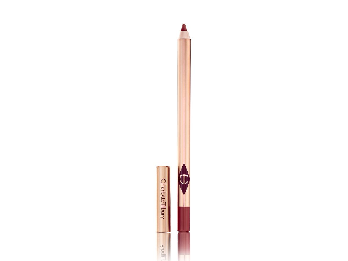 A lip liner pencil in a maroon shade with its lid next to it. 