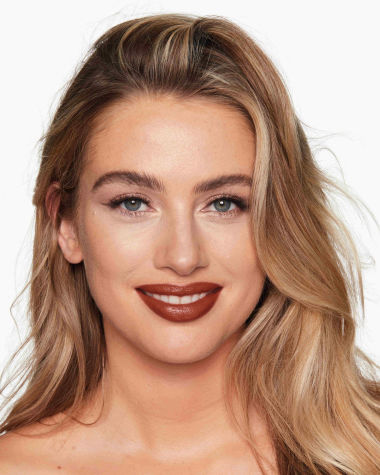 Fair-tone model with grey eyes wearing a moisturising lipstick balm in a soft brown shade with a high-shine finish.