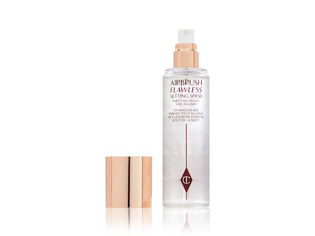 A setting spray in a clear bottle with a gold-coloured lid placed next to it.