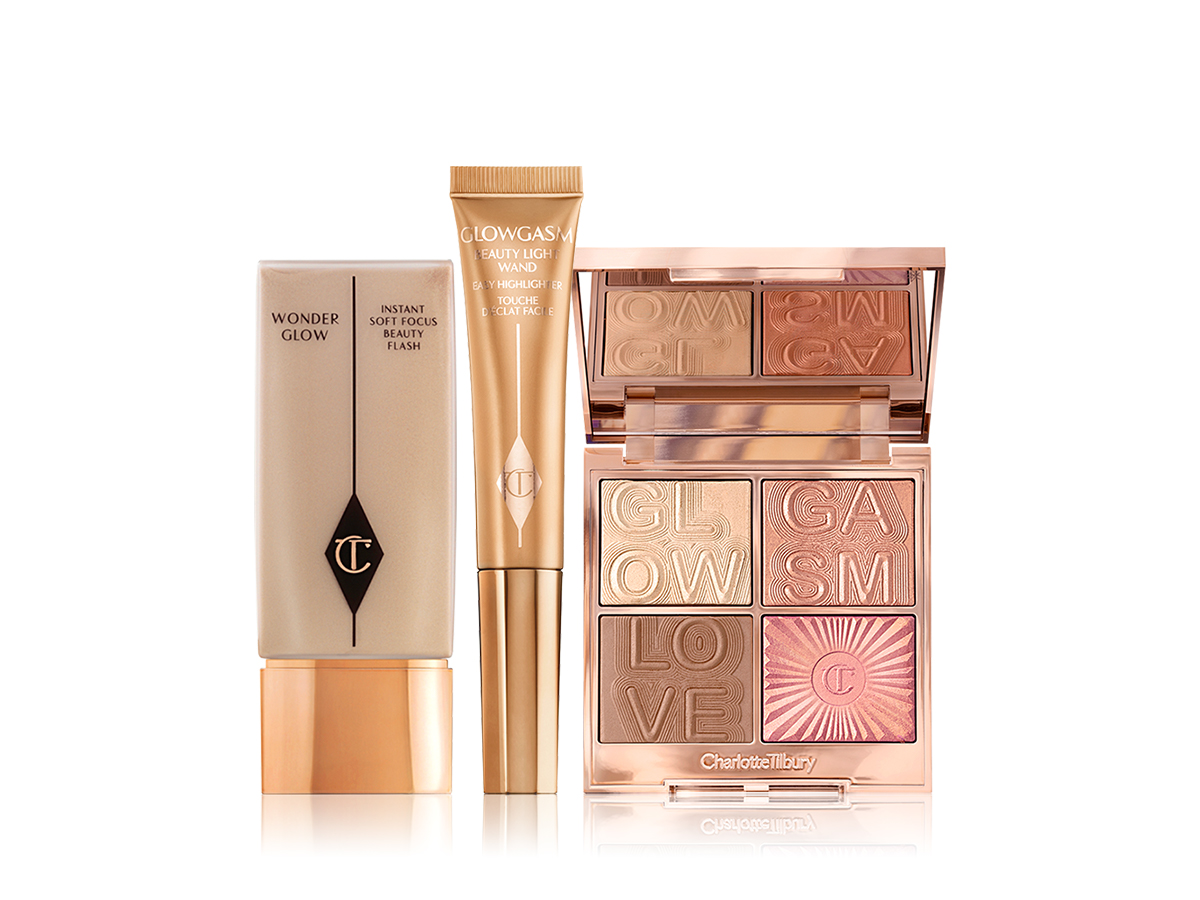 Foundation in a light beige shade with gold-coloured lid, liquid highlighter wand in hiney-gold colour, and glowy face palette with two highlighters, bronzer, and blush. 