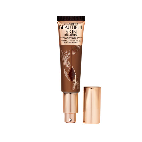 An open foundation wand in gold packaging with a pump dispenser and a dark-brown-coloured body to show the shade of the foundation inside. 