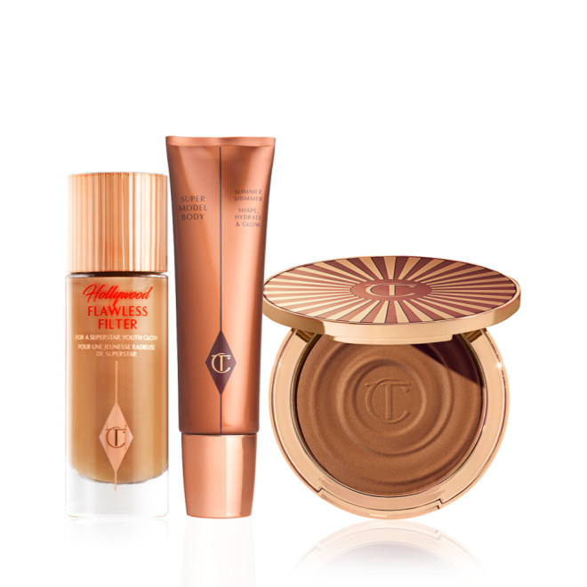 Glowy primer in a frosted glass bottle with a gold-coloured lid, body highlighter wand, and cream bronzer compact.