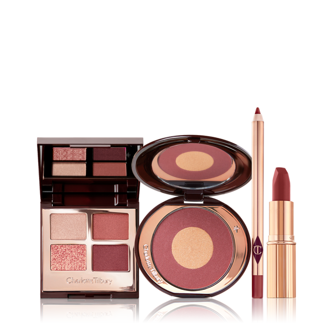 An open, quad eyeshadow palette with a mirrored-lid with eyeshadows in shades of cream, rose gold, berry-pink, and redwood, a two-tone blush compact in berry-pink and honey-gold, lip liner pencil in a berry-pink shade, and matte lipstick in a berry red pink shade.