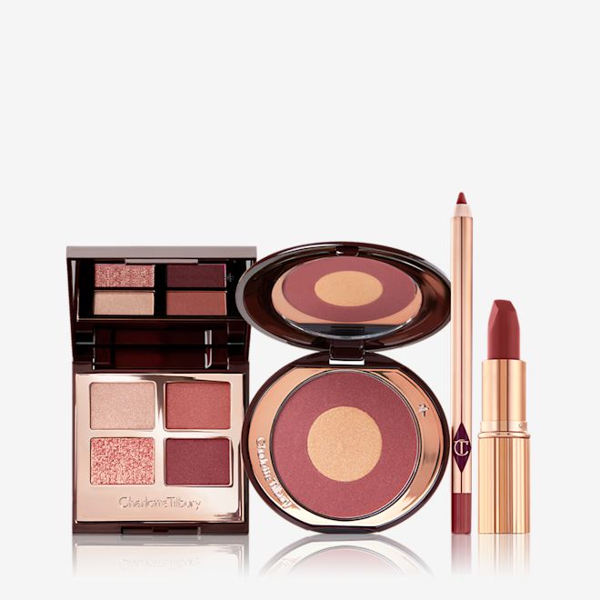 Walk of No Shame Makeup Secrets kit open An open, quad eyeshadow palette with a mirrored-lid with eyeshadows in shades of cream, rose gold, berry-pink, and redwood, a two-tone blush compact in berry-pink and honey-gold, lip liner pencil in a berry-pink shade, and matte lipstick in a berry red pink shade.