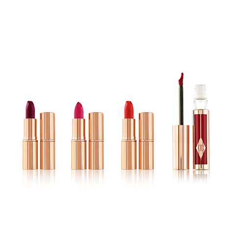 Three open lipsticks with an open lip gloss in bright shades of pink, red, and purple with their lids next to them. 