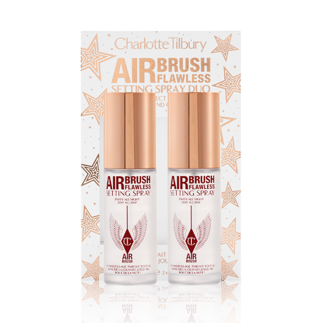 Two, identical, mini setting sprays with gold-coloured lids and their white and gold-coloured packaging box behind them with gold stars printed all over with text on the box that reads, 'Charlotte Tilbury. Airbrush Flawless Setting Spray duo'