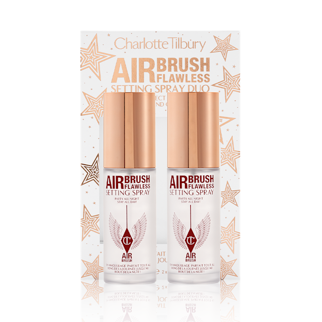 Airbrush Flawless Setting Spray Duo with box Two, identical, mini setting sprays with gold-coloured lids and their white and gold-coloured packaging box behind them with gold stars printed all over with text on the box that reads, 'Charlotte Tilbury. Airbrush Flawless Setting Spray duo'