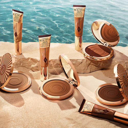 Four, open cream bronzer compacts with mirrored lids in light brown, medium brown, dark brown, and black-brown shades with gold-coloured bodies and lids, along with four, liquid contour wands in similar shades.