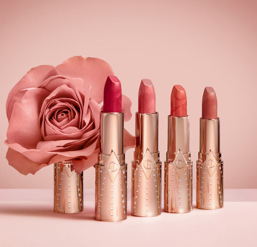 Four, open, nude lipsticks in shades of brown, peach, pink, and red with gold-coloured tubed with rhinestones studded.