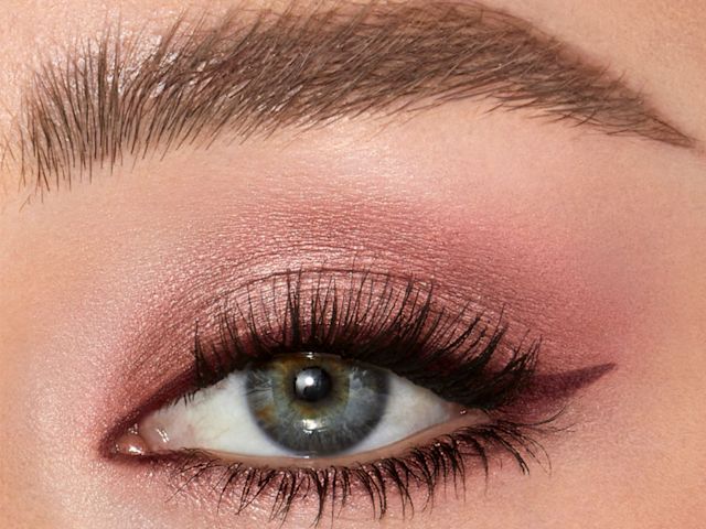 Single-eye close-up of a fair-tone model with blue eyes wearing shimmery rose gold cream eyeshadow.