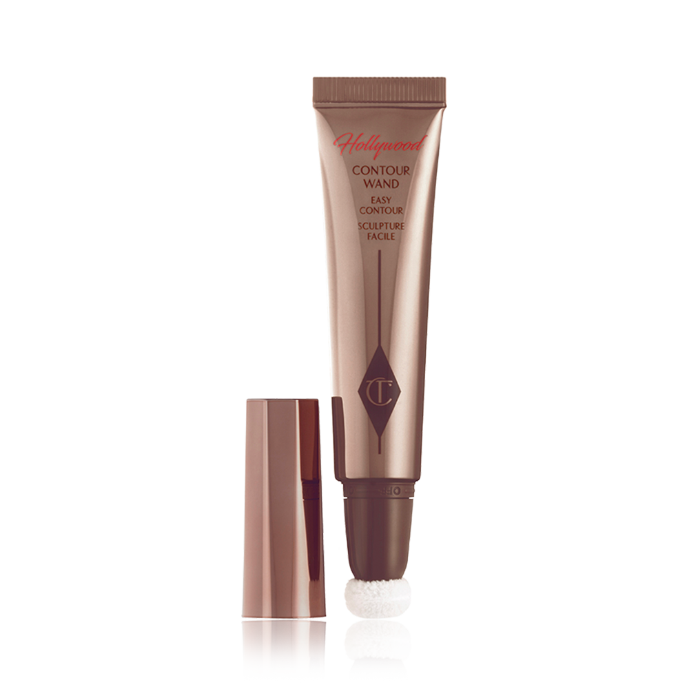 An open, liquid contour wand in a deep bronze-coloured, reflective packaging with a soft, sponge-tip applicator at the end and its lid next to it.