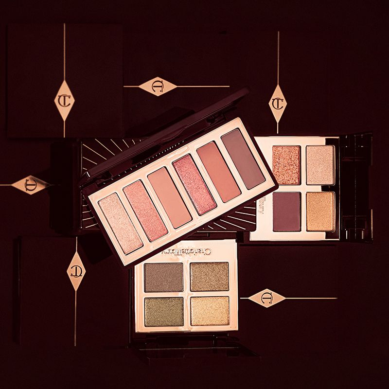 three open eyeshadow palettes, two quad and one six-colour palette in shades of pink, peach, brown, golden, and green. 