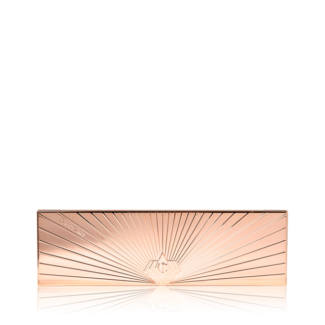 A closed eyeshadow palette in a slim, rectangular shape with a reflective, rose gold finish and symmetrical, starburst-style lines all across the lid.