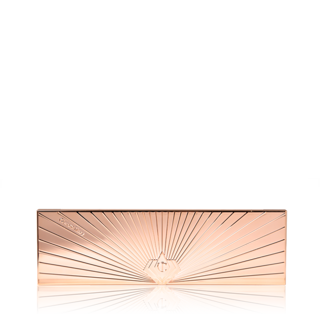 A closed eyeshadow palette in a slim, rectangular shape with a reflective, rose gold finish and symmetrical, starburst-style lines all across the lid.