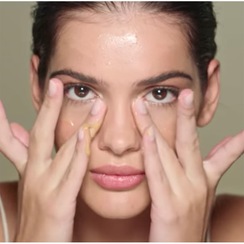 Fair-skinned, brunette model applying serum on her face.