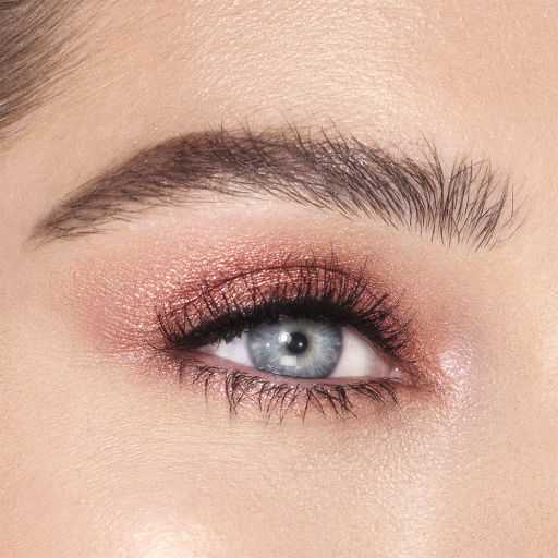 Single-eye close-up of a fair-tone model with blue eyes wearing shimmery berry-pink eyeshadow.