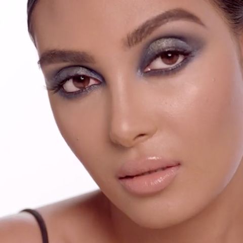Un mannequin à la peau claire, aux cheveux bruns et aux yeux marron portant un rouge à lèvres pêche-nude et un maquillage des yeux gris charbonneux. 