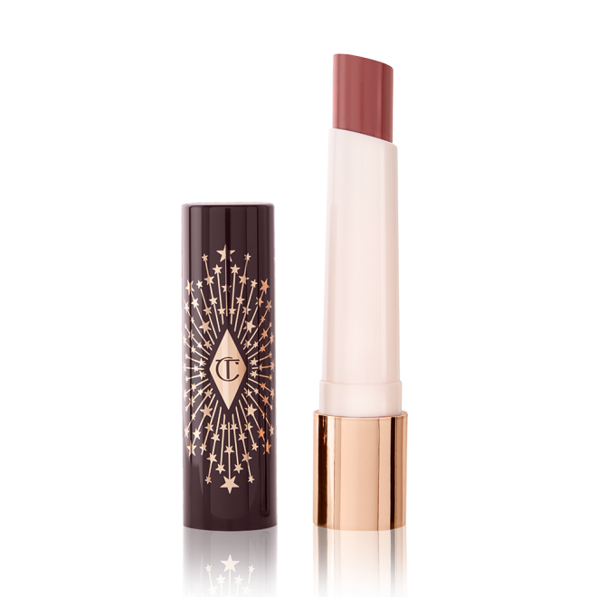 An open, moisturizing lipstick lip balm in a nude pink shade with a black and gold-coloured cover. 