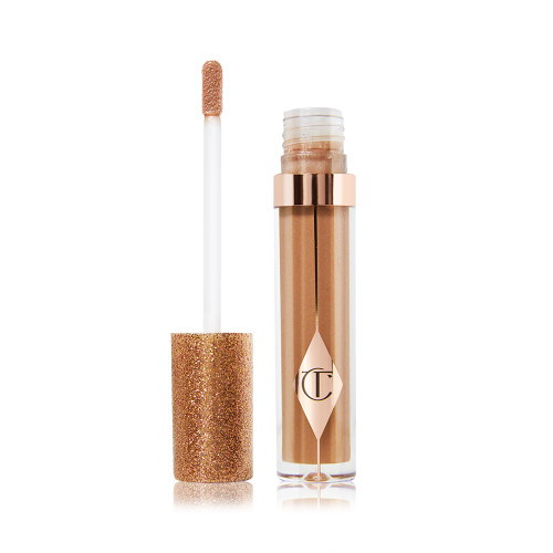 An open, shimmery gold-coloured lip gloss with rose gold sparkles with its doe-foot applicator next to it. 